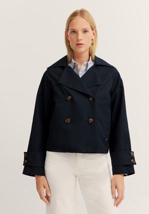 Dunkelnavyblaues, kurzes Jacket mit doppelten Knöpfen, breiten Revers und auffälligen Manschetten. Der Stoff wirkt glatt und langlebig.