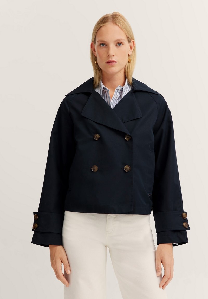 Dark navy cropped jacket with double-breasted buttons, wide lapels, and prominent cuffs. Fabric appears smooth and durable.