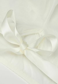 White lingerie with a delicate satin ribbon tie, featuring a sheer fabric and subtle textured pattern along the edges.