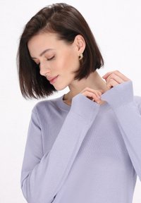 Maglione a maniche lunghe di colore viola chiaro, con polsini a costine, vestibilità rilassata, collo a giro e texture morbida. Nessun motivo o hardware visibile.
