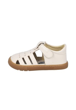Sandalia infantil de cuero blanco con cierre de velcro, diseño perforado y suela de goma marrón, mostrada de lado sobre un fondo blanco.