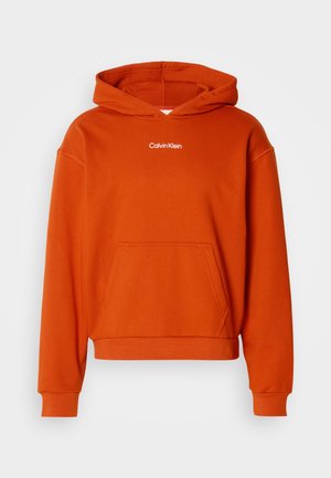 Orangener Kapuzenpullover mit einer Kängurutasche und weißem "Calvin Klein"-Logo auf der Brust. Hergestellt aus weichem, texturiertem Stoff.