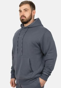 Sweater met trekkoord en capuchon in mediumgrijs, met een voorzak en een gestructureerde stof met een subtiel logo op de kraag en de mouw.