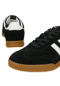Sneakers en daim noir avec des bandes blanches et des semelles en caoutchouc naturel, vues de face et de dos sur fond blanc.