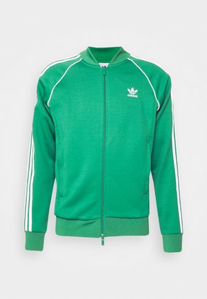 Zeleni poliester jakna z zadrgo in belimi črtami, rebrastimi manšetami in ovratnikom. Ima majhen bel logotip na prsih.