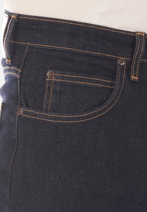 Dunkelblaue Jeans aus Denim mit orangefarbener Naht, schlanker Schnitt, Fronttasche und Kupferriegeln in der Nähe des Taillenbundes und der Tasche.