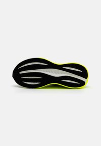 Schuhsohle mit einer schwarzen Gummibasis, weißem Zwischensohlenteil und neon-gelbem Akzent. Mit Rillen strukturiert für Traktion und Flexibilität.