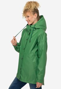 Giacca impermeabile verde con cappuccio, coulisse regolabili, bottoni a pressione e tasche laterali. Presenta una texture liscia e una vestibilità comoda.
