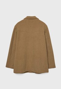Veste en daim marron avec un col, des détails surpiqués et une coupe décontractée. Elle présente un empiècement au dos et un ourlet incurvé pour un design supplémentaire.