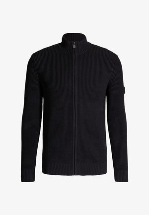 Schwarzer Pullover mit Reißverschluss, strukturierter Strickoptik, hohem Kragen sowie gerippten Bündchen und Saum. Mit einem Logo-Patch am linken Ärmel.