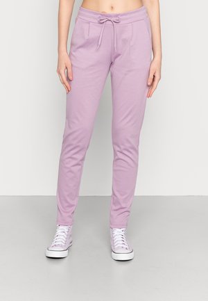Ljust rosa joggers i mjukt tyg, med dragsko i midjan, sidofickor och tapered ben, matchat med vita sneakers.