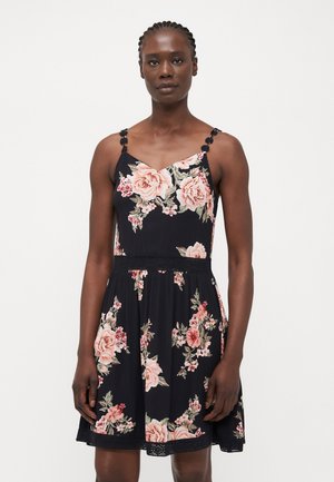 Rochie florală cu un fundal negru, având trandafiri roz. Bretele tip spaghetti cu accente decorative, bust ajustat și fustă evazată.