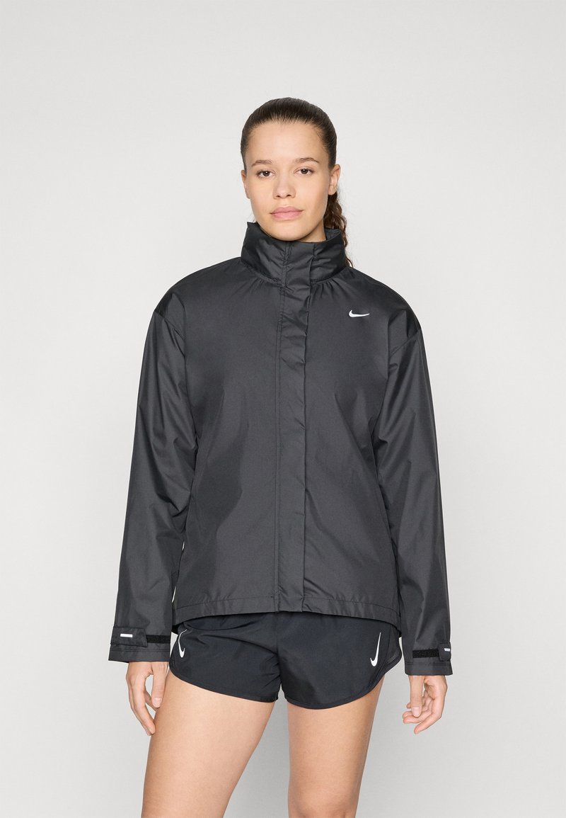 Crna Nike jakna s visokim ovratnikom, zatvaranjem na zip i minimalističkim dizajnom. Glatka tekstura tkanine, s malim bijelim logotipom na prsima.