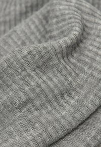 Šedá žebrovaná tkanina s měkkou texturou, obsahující jemné variace v odstínu a konzistentní vzor vyvýšených linií.