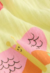 Gul stof med et sommerfuglemotiv i pink, orange og sort med et smilende ansigt, tekstureret overflade og klare farver.