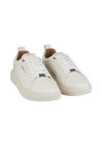 Sneakers in pelle bianca con una texture liscia, caratterizzati da una punta arrotondata, design con lacci e piccoli dettagli del logo. Suola in gomma e cuciture sottili.