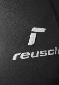 Schwarzer Stoff mit einem strukturierten weißen Logo von "Reusch", das auffällig platziert ist, mit kräftigen, klaren Linien und einer glatten Oberfläche.