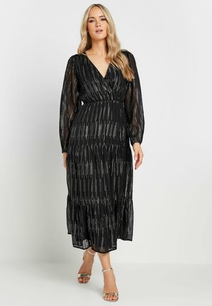 Zwarte, doorschijnende maxi-jurk met lange mouwen, een V-halslijn, een gelaagd ontwerp en zilveren verticale strepen. Voorzien van een elastische taille.