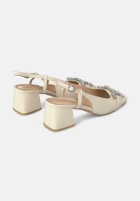 Talons escarpins beige avec une finition texturée, un bout-pointu, un talon bloc et des accents décoratifs en rhinestones sur les brides.