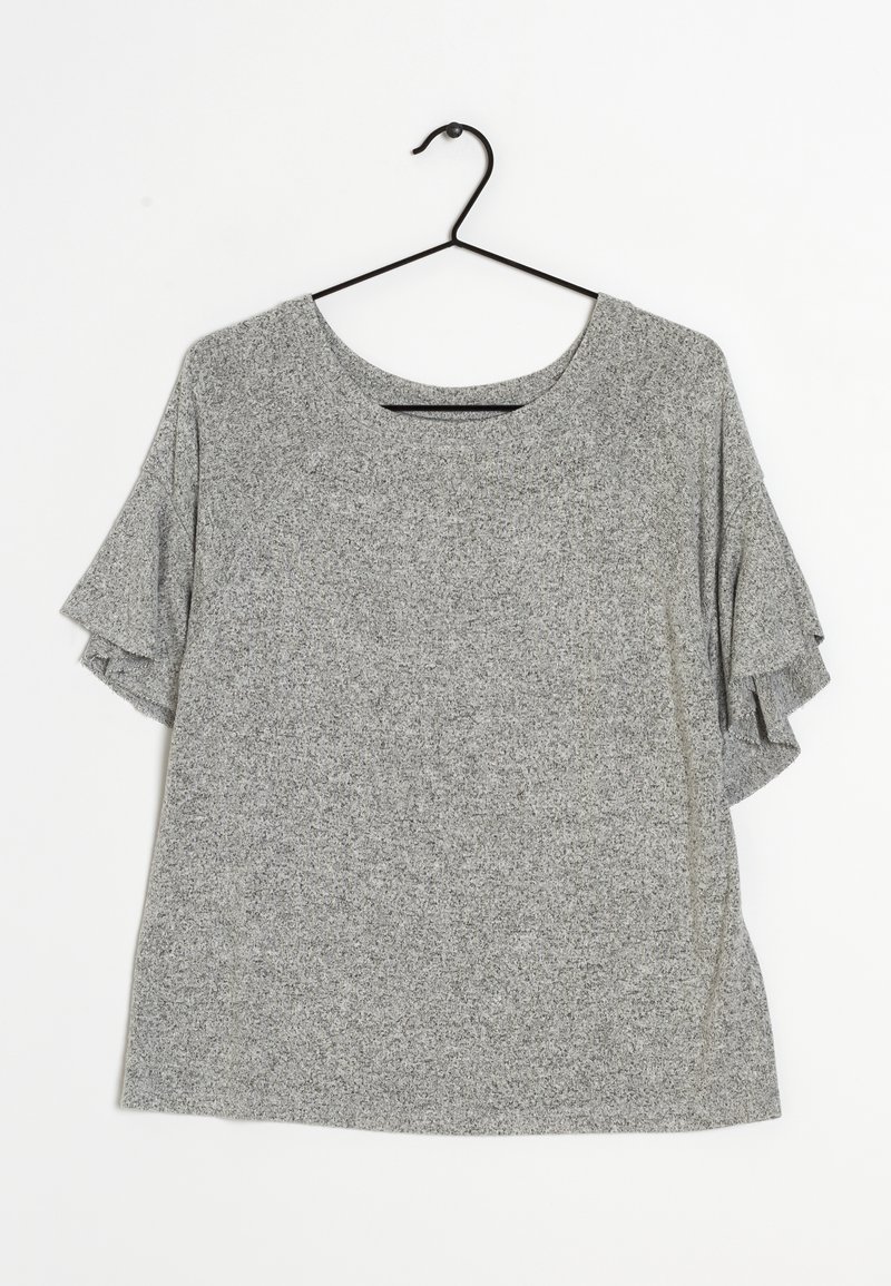 Top gris de manga corta con cuello redondo, que presenta acentos con volantes en las mangas y una tela suave y texturizada. Cuelga de un gancho negro.