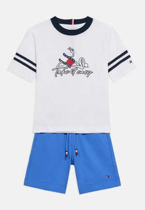 Hvid kortærmet T-shirt med navy-blå krave og grafik "Take it Easy", kombineret med blå shorts med snøre, begge med små Tommy Hilfiger-logoer.