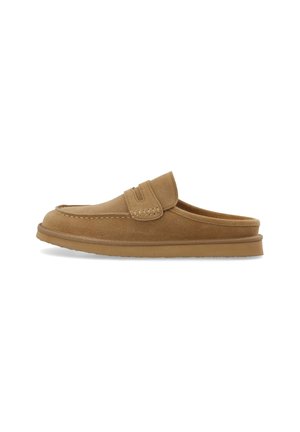 Mule en daim marron à enfiler avec une semelle plate et une couture style mocassin sur le dessus et autour des côtés.