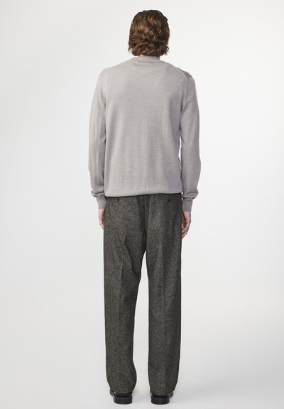 Gray knit sweater with long sleeves, paired with tailored black textured pants, viewed from the back, highlighting the outfit's shape and color.