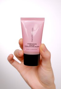 Rosa squeeze-tub med svart bas, märkt "Complexion Rescue Highlighting Blush." Slät, glansig textur; minimalistisk design.