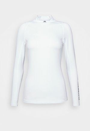 Top de manga larga blanco hecho de una tela suave y ligera con un cuello alto y detalles en negro en una de las mangas.