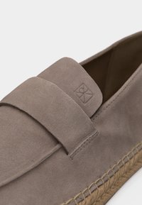 Παπούτσι από ταουπε σουέντ με σόλα από πλεγμένο τζούτ και ανάγλυφο λογότυπο στο μπροστινό πάνω μέρος.