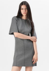 Grå kortärmad klänning med skräddarsydd passform, gjord av textil med synliga sömmar och rund halsringning. Enkelt och modernt design.