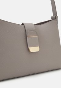 Szara syntetyczna torebka o fakturowanej powierzchni, z zapięciem z złotym okuciem i cienkim regulowanym paskiem. Strukturalna sylwetka.