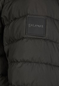 Sort pufjakke med quiltet tekstur, der har et rektangulært logo-patch med "CALAMAR" i en mat finish på stoffet.
