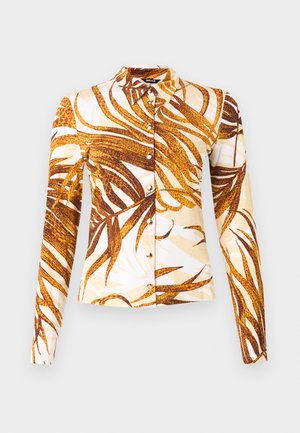 Camisa de manga larga con botones y cuello puntiagudo, con un llamativo estampado abstracto de hojas en tonos marrón y beige sobre un fondo blanco.