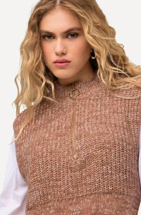 Top senza maniche lavorato a maglia in tonalità pescate calde, con colletto alto e dettagli in zip dorata. Il filato texture aggiunge dimensione al design.