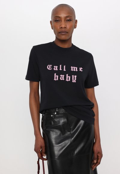 Mustade lühikeste varrukatega t-särk, millel on fraas "Call me baby" roosas dekoratiivses fondis, koos musta nahkse seeliku ja isegi.