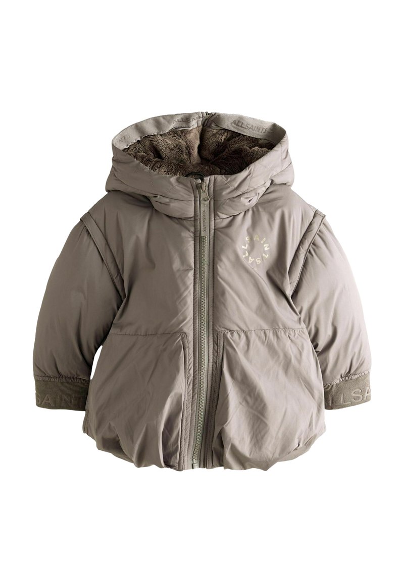 Pufferväst i dämpad beige, med huva och hel dragkedja. Mjuk innerfoder, ribbade ärmslut och logotypdetalj på bröstet.