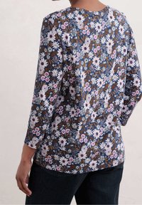 Långärmad blommig topp med marinblå bakgrund, vita och rosa blommor samt bruna accenter. Det mjuka tyget har en slät yta och avslappnad passform.