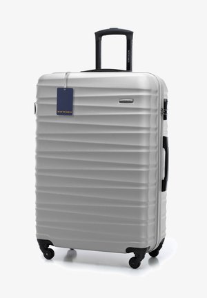 Stříbrný tvrdý kufr s vertikálními drážkami, teleskopickou rukojetí, dvojitými koly a připojeným štítkem na zavazadlo. Viditelné logo značky.
