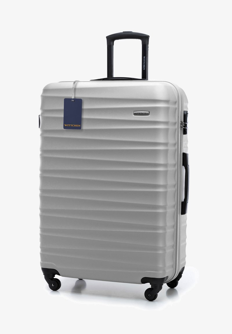 Stříbrný tvrdý kufr s vertikálními drážkami, teleskopickou rukojetí, dvojitými koly a připojeným štítkem na zavazadlo. Viditelné logo značky.