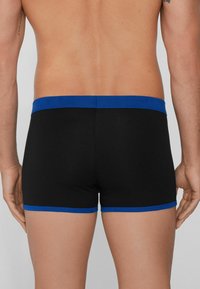 Boxers ajustados negros con una cinturilla elástica azul y acentos, fabricados con un tejido suave y elástico, que presentan un diseño simple y funcional.