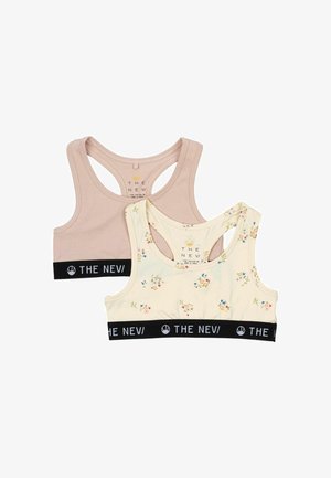 Dos sujetadores recortados: uno en tono beige claro y otro en crema con un patrón floral. Ambos cuentan con una banda elástica negra con logo blanco y diseño de espalda de nadadora.