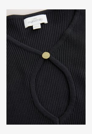 Crna rebrasta trudnička majica s okruglim zlatnim gumbom na izrezu. Tkanina je teksturirana i mekana s prilagođenim krojem.