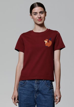 Kastanienbraunes Baumwoll-T-Shirt mit einem gedruckten orangefarbenen Fuchs-Design im Bereich der linken Brust. Kurze Ärmel und ein klassischer Rundhalsausschnitt.