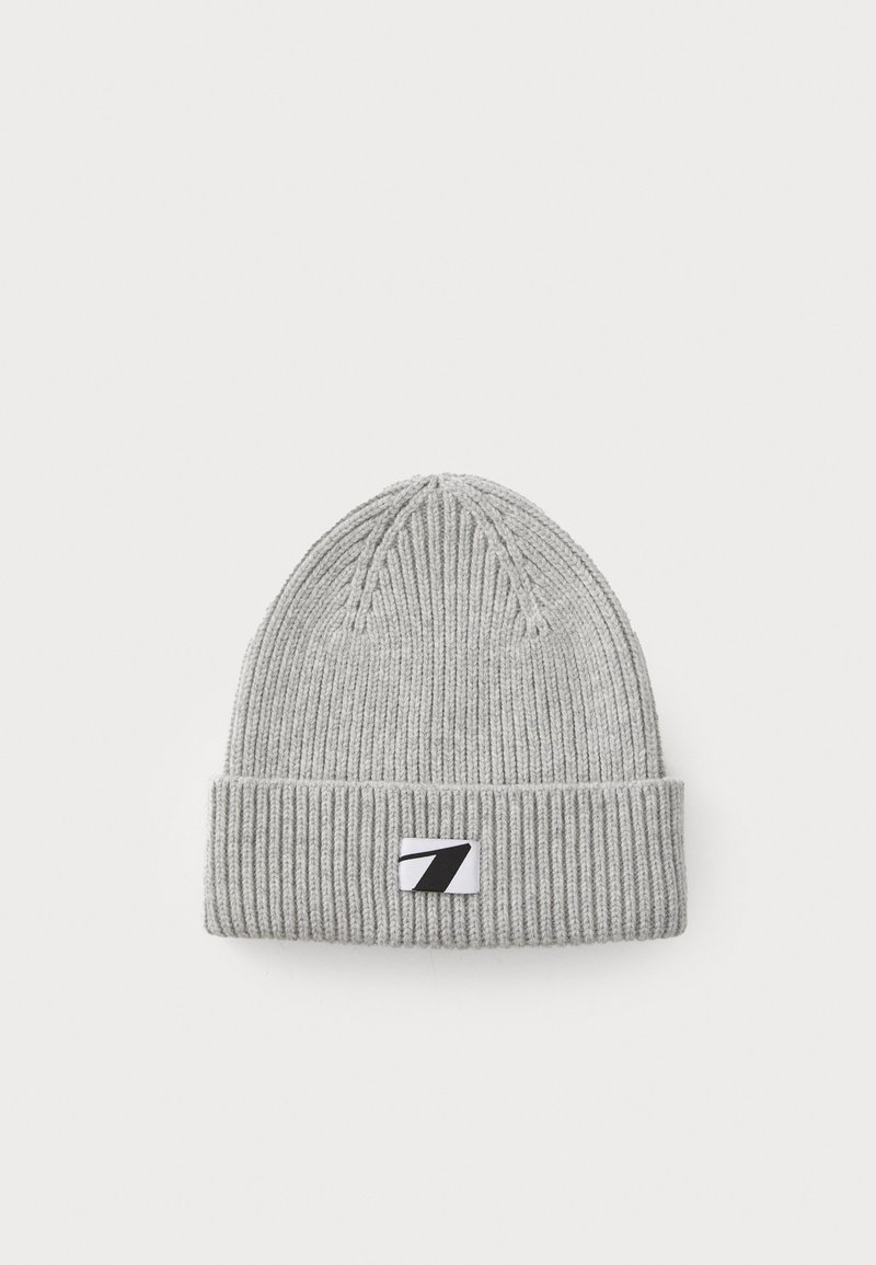 Bonnet en tricot gris avec une texture côtelée et un revers replié, présentant un petit patch logo noir et blanc à l'avant.