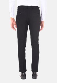 Pantaloni neri a vestibilità slim, dotati di tasche posteriori e passanti per cintura. Tessuto dalla trama liscia e design a gamba dritta, abbinati a scarpe eleganti.