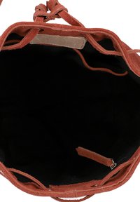 Samt Bucket Bag in rostfarben mit einer weichen Textur. Das Innere ist mit einem dunklen Futter und einer kleinen Reißverschlusstasche ausgestattet. Design mit Kordelzugverschluss.