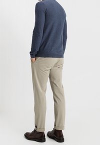 Marinblå tröja i stickad tyg, i kombination med ljusbeige chinos och mörkbruna kängor, med uppvikta ärmslut och sidofickor.