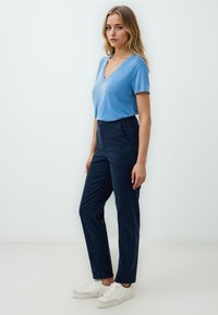 T-shirt azzurro chiaro a collo a V abbinato a pantaloni dritti blu navy e sneakers bianche. Tessuto morbido, design semplice, senza motivi o decorazioni.
