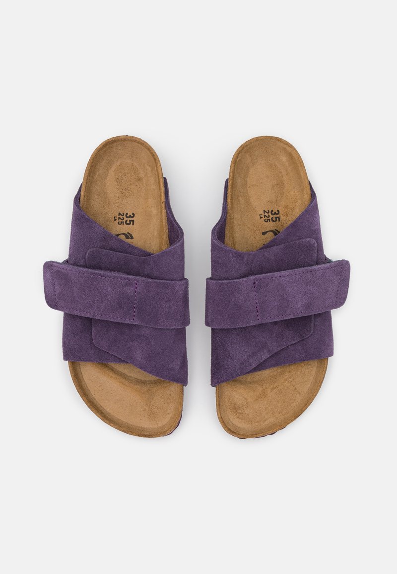 Lila Wildleder-Sandalen mit einem breiten, gekreuzten Riemendesign. Konturierte Korksohle mit sichtbarer Textur und Größenmarkierungen auf der Innensohle.